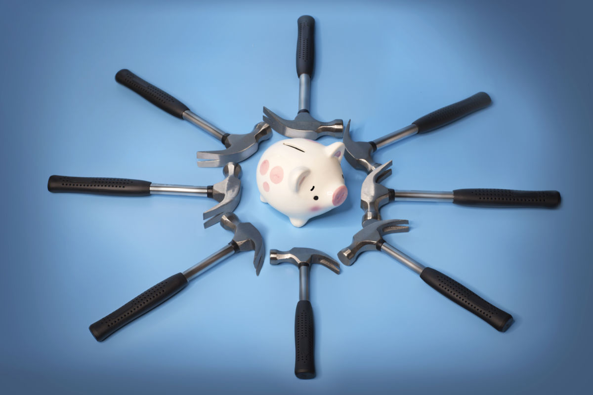 Hammers encircle a worried ceramic piggy bank