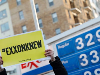 A protester holds a yellow sign reading "EXXON KNEW" during a demonstration