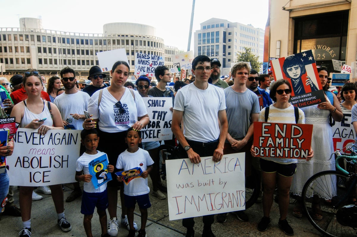 Protesters stand near eachother while holding signs