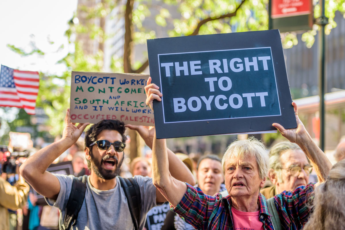 People hold signs supporting a boycott of Israel