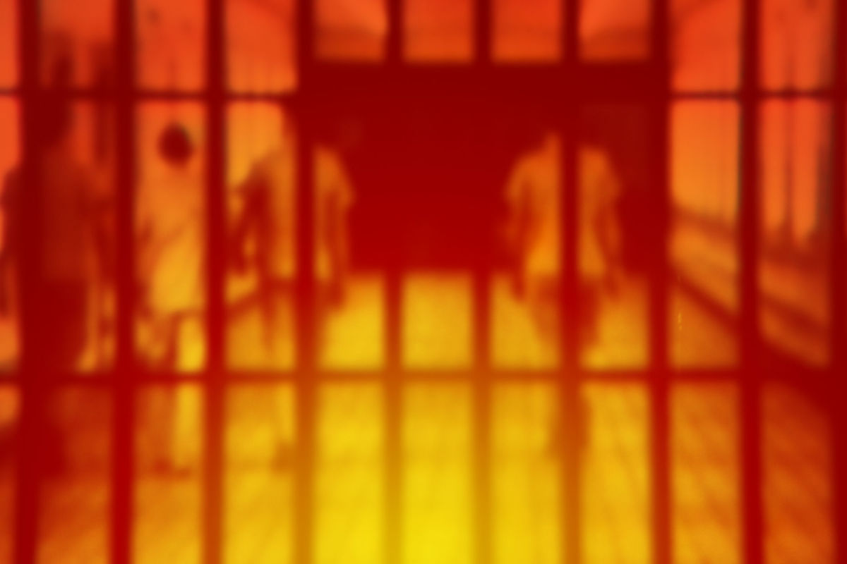 A blurred image of prisoners behind bars overlaid with red and yellow