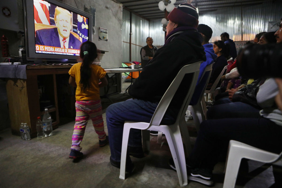 Migrants view a live televised speech by President Trump at a shelter for migrants on January 8, 2019, in Tijuana, Mexico.