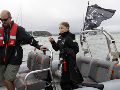 Greta Thurnberg waves while on a boat