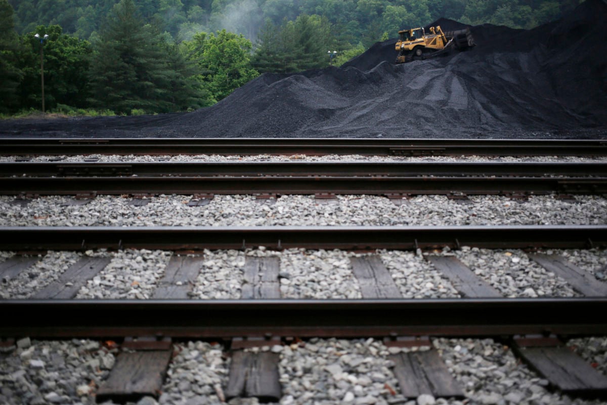 A large pile of coal stands behind empty railway tracks
