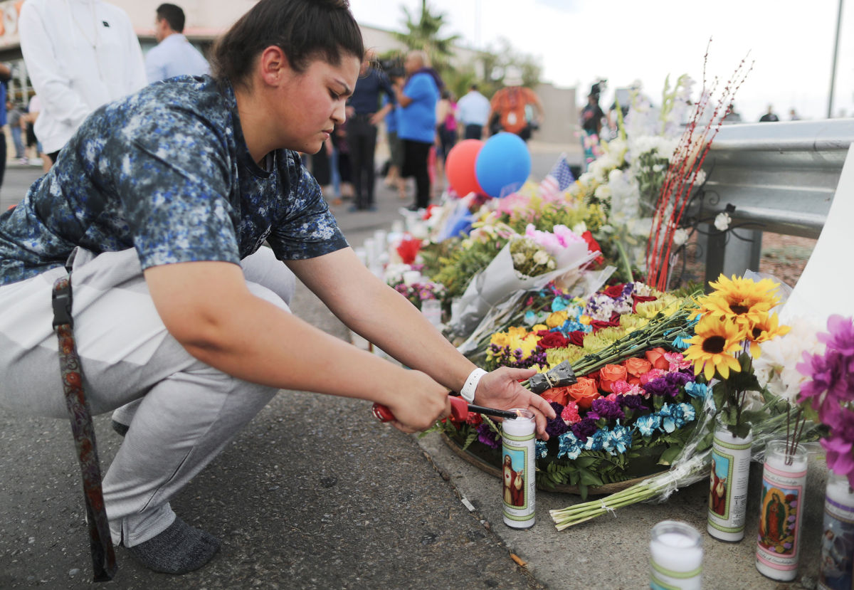 A woman kneels to lay flowers at a memorial