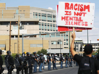 An anti-Trump protestor holds a sign as police are lined up outside University Medical Center, where President Trump was visiting shooting victims, following a mass shooting which left at least 22 people dead, on August 7, 2019, in El Paso, Texas.