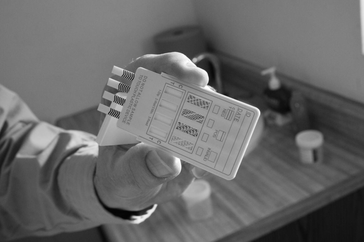 A person holds a drug test in a black and white photo