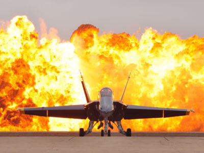 An F/A-18 Hornet aircraft sits on the flight line as a wall of fire detonates behind it during an air show at Marine Corps Air Station Miramar, California, October 3, 2010.