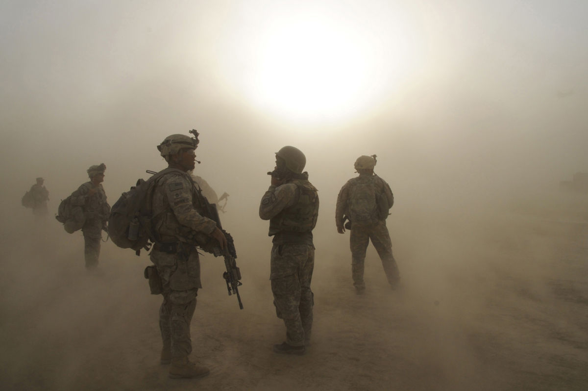 Soldiers stand amidst clouds of dust