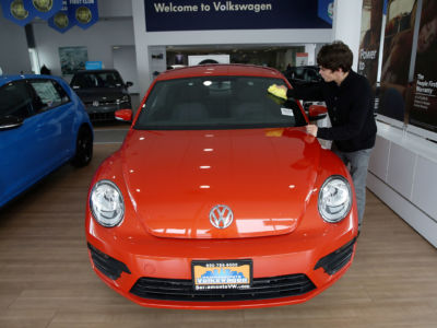 A worker shines a red Volkswagen