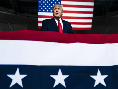 Dondald trump speaks behind a u.s. flag