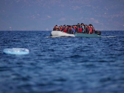 Migrants, some with orange life vests, are seen in a small raft