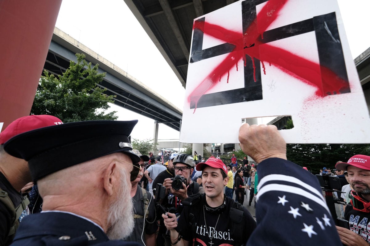 A retired paramedic confronts Proud Boys as they wait wait to get into vehicles to go to another location after marching across the Hawthorne Bridge in Portland, Oregon, on August 17, 2019.