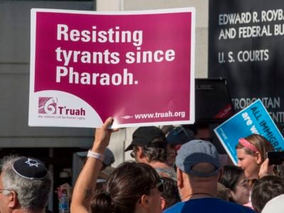 A protester holds a sign reading "Resisting tyrants since Pharoah" during a protest