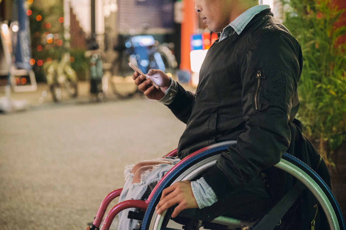A man in a wheelchair checks his phone