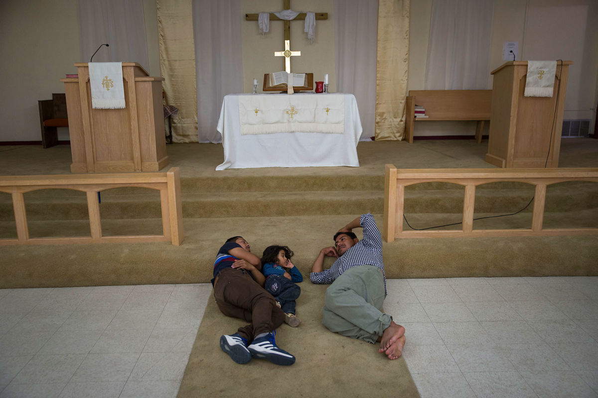A family sleeps in front of the altar in a Christian church