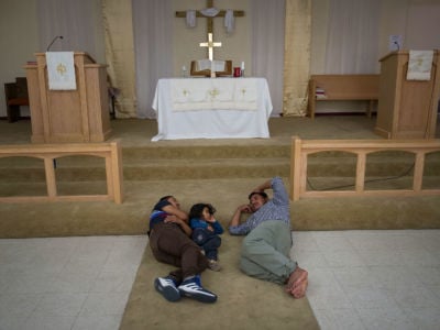 A family sleeps in front of the altar in a Christian church