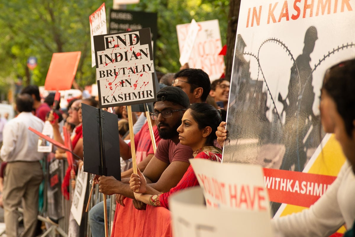 People display signs during a protest in solidarity with Kashmir