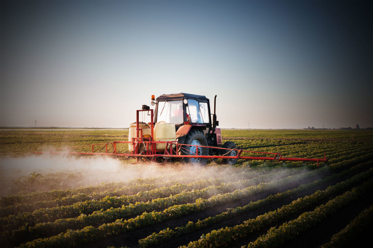 A tractor sprays fields of crops