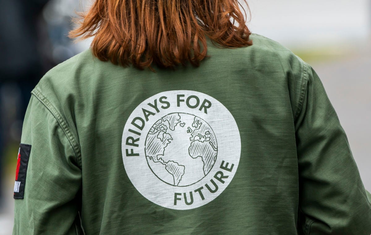 An activist wears a shirt with "Fridays for Future" printed on the back around an image of the Earth