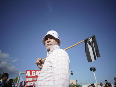 A man holds a black and white Puerto Rican flag during a protest