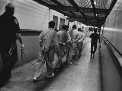 A group of men is led down a hallway in California's Pelican Bay prison, where many people spend years in solitary confinement and only leave their cells with full chains on.