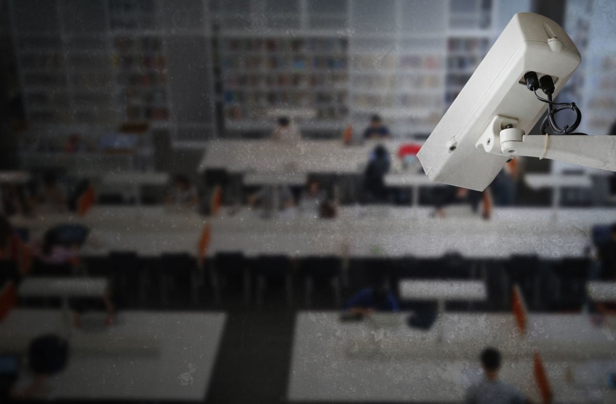 A surveillance camera is pointed down at a school library full of students