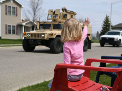 A child waves to an airman in the hatch of an armored vehicle during a parade to commemorate National Police Week at Minot Air Force Base, North Dakota, May 12, 2019.