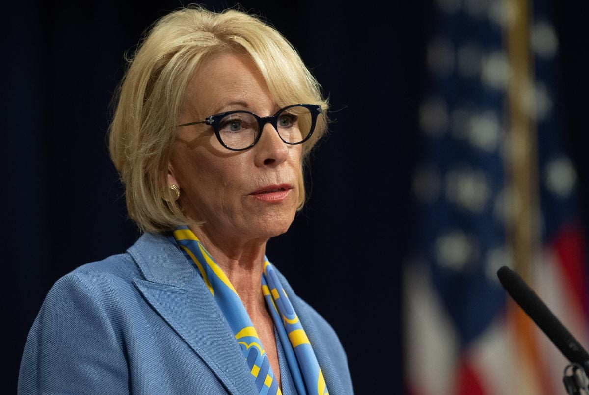 Betsy DeVos stands in front of a microphone