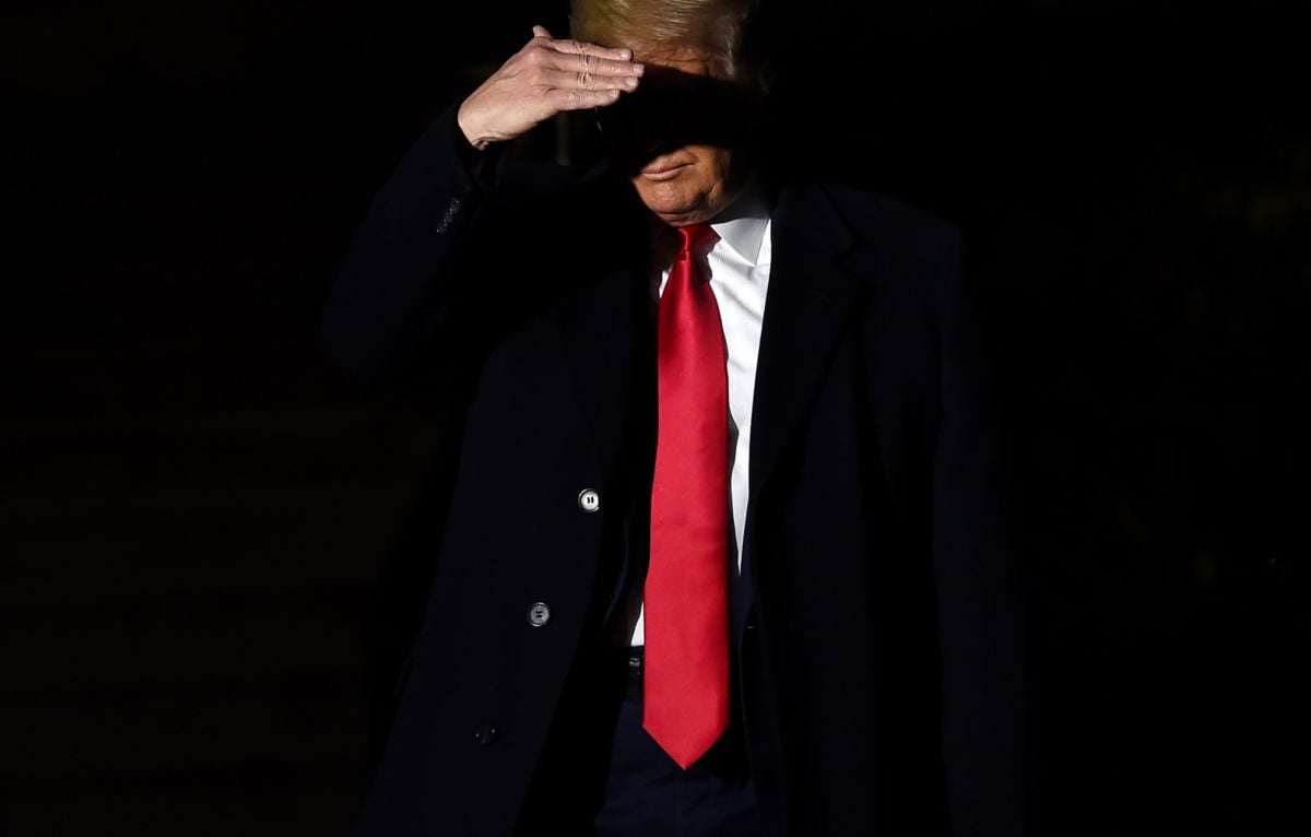 Donald Trump sheilds his eyes from a spotlght while walking in the dark
