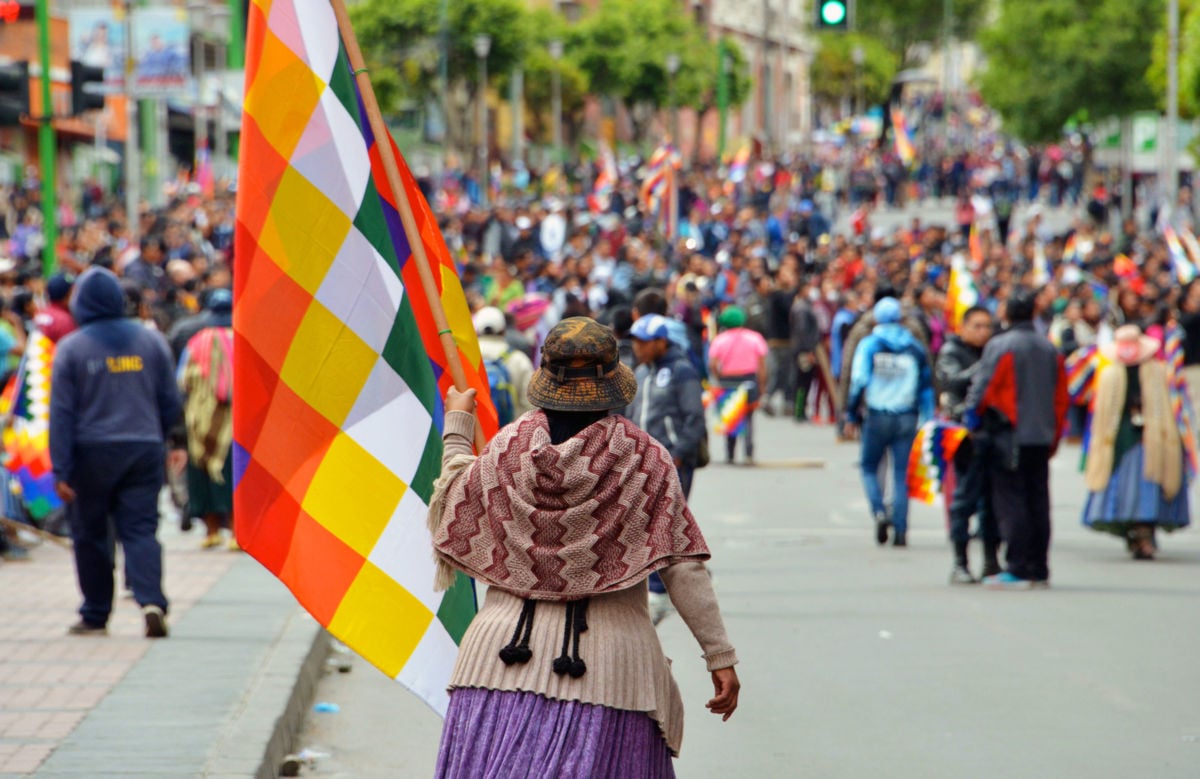 A woman holds a checkered Bolivian Indigenous flag during a massive street protest