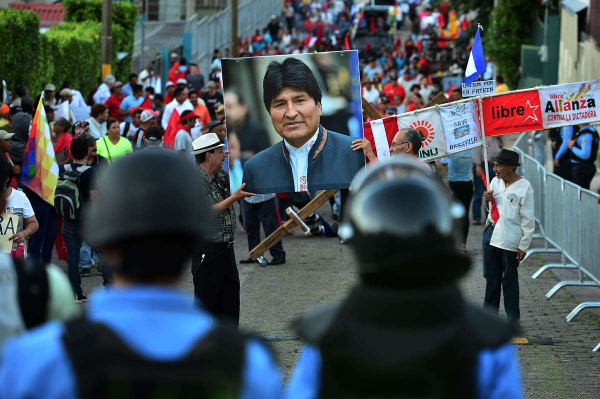 Protesters march while displaying a photo of Bolivian ex-president Evo Morales