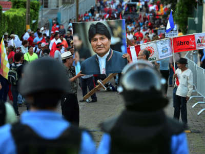 Protesters march while displaying a photo of Bolivian ex-president Evo Morales