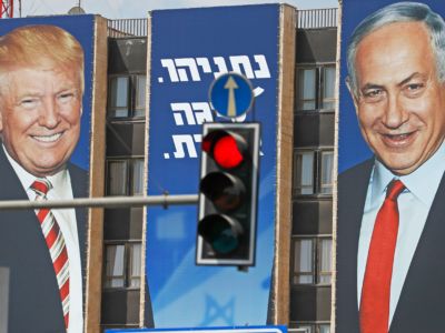 A banner depicting Trump and Netanyahu is displayed on the side of a building