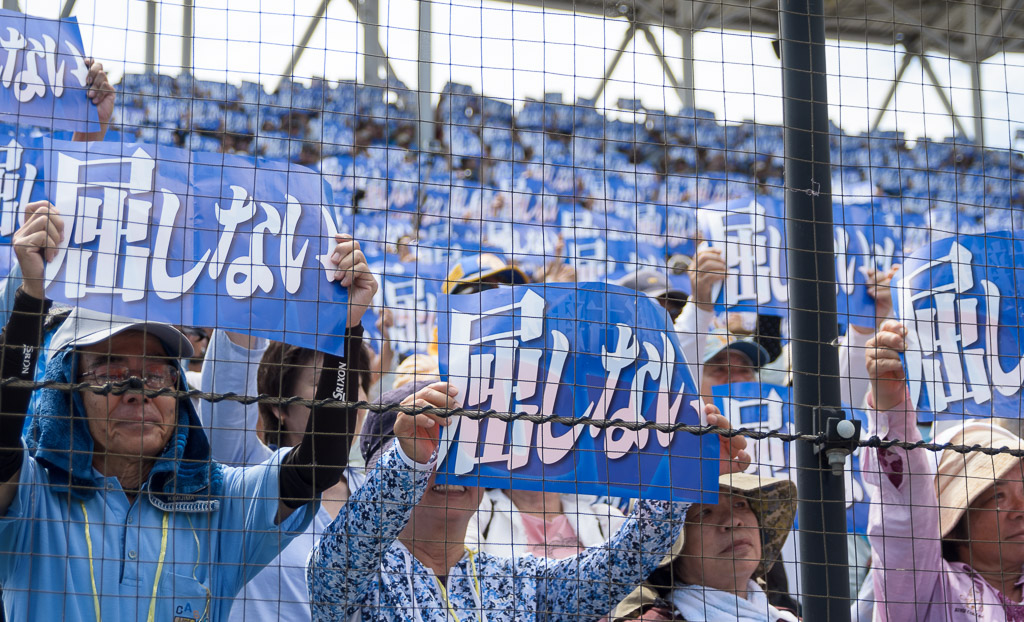 People raise "Never Surrender" signs at a rally against Henoko relocation at Okinawa Cellular Stadium Naha, May 1, 2015.