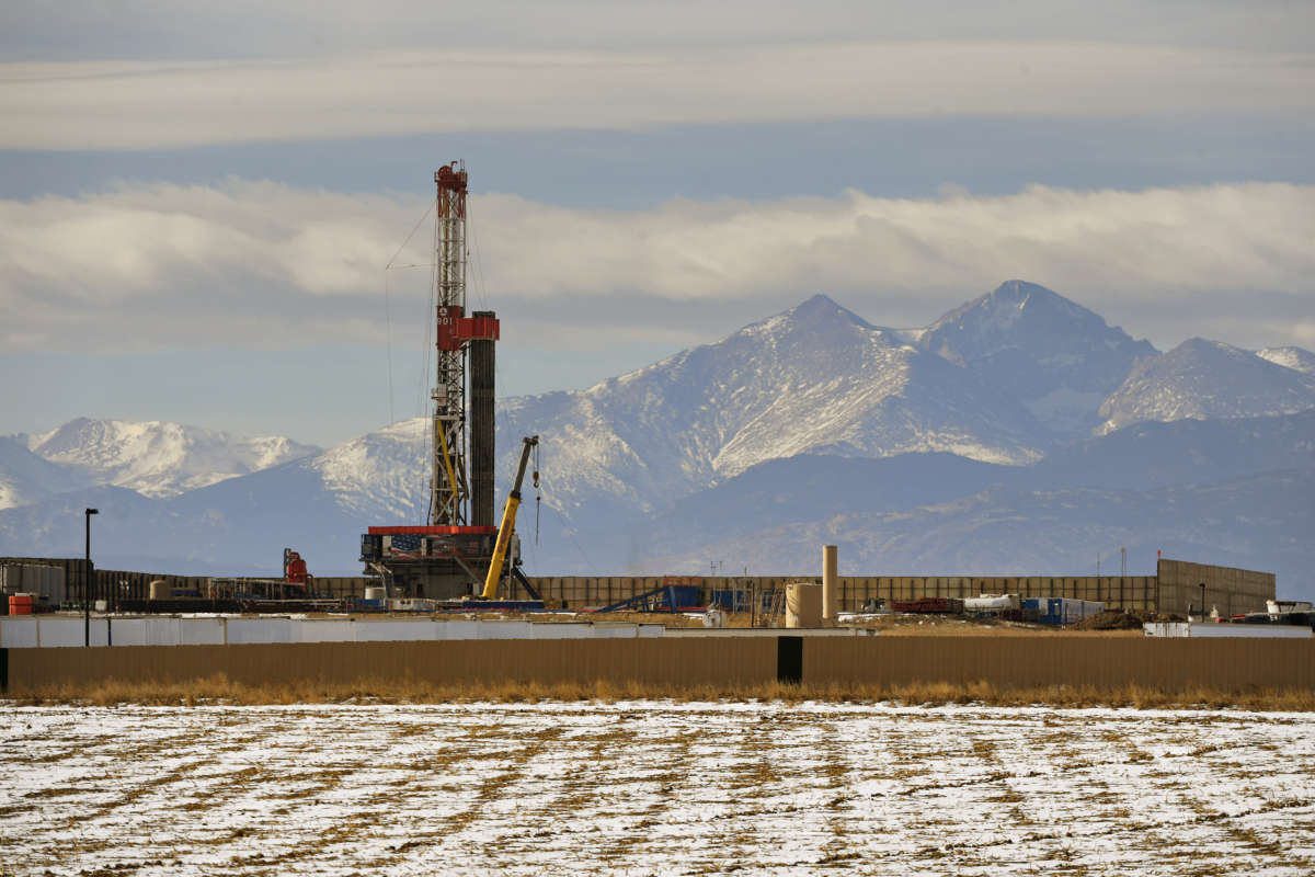 A fracking tower stands in front of a backdrop of mountains