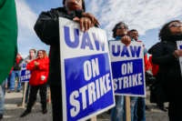 People stand holding signs reading "UAW WORKERS ON STRIKE"