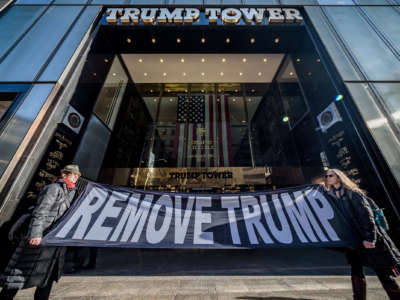 Activists hold a sign reading "REMOVE TRUMP" in front of Trump Tower