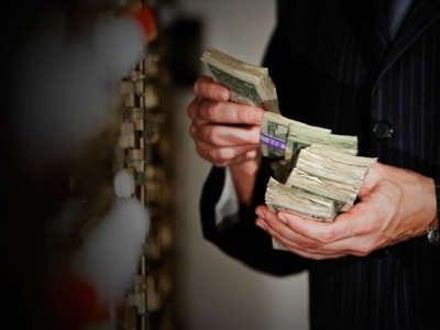 A man counts stacks of money outside of a bank vault
