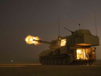A tank fires off a shell at night