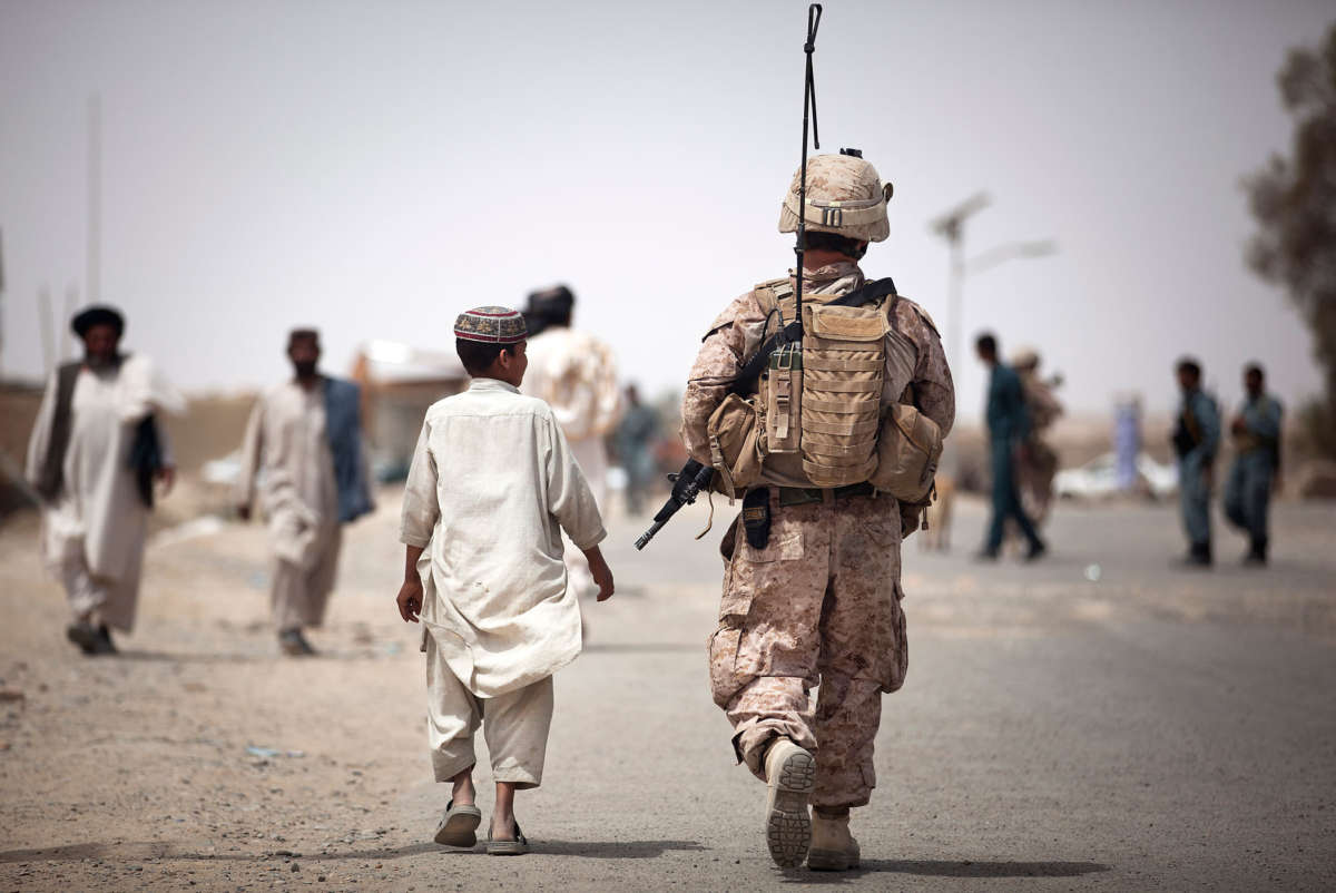 An Afghan boy walks alongside a U.S. Marine on a security patrol in Helmand Province, Afghanistan, on April 17, 2012.