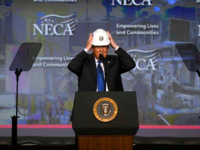 U.S. President Donald Trump puts on a hard hat as he addresses the National Electrical Contractors Association convention on October 2, 2018 in Philadelphia, Pennsylvania.