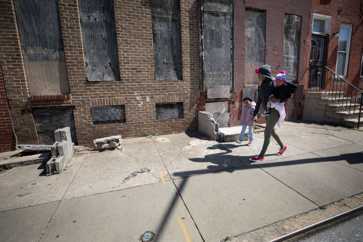 A woman walks with her two daughters through the Upton neighborhood of Baltimore, Maryland, on April 3, 2019. Life expectancy in Upton is 68.2 years, while the average for the city is 73.6, according to Baltimore City data from 2017.