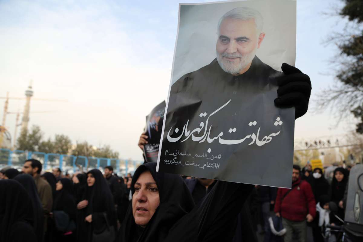 A woman holds a photo of Qasem Soleimani during a demonstration
