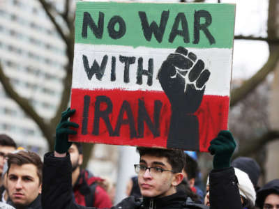 A protester holds a sign reading "No War with Iran" as