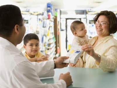 A Latina mom with her kids picks up a perscription