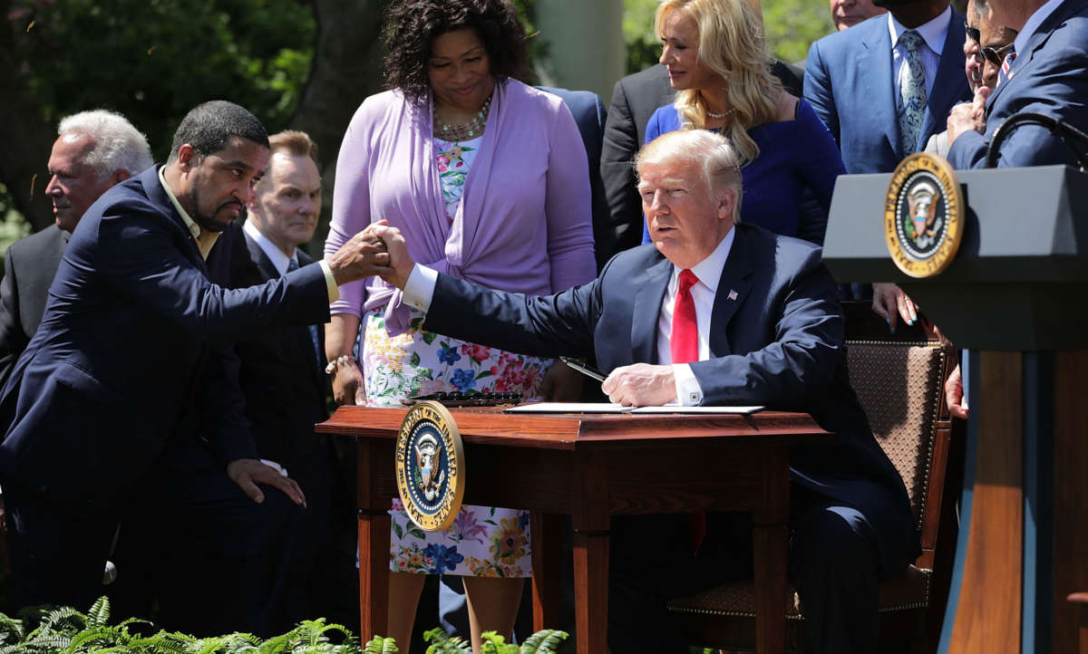 President Trump shakes hands with Pastor Darrell Scott before signing an executive order during an event in the Rose Garden, May 3, 2018, in Washington, D.C. A group run by Scott gave away $25,000 in cash-stuffed envelopes at events promoting Trump.