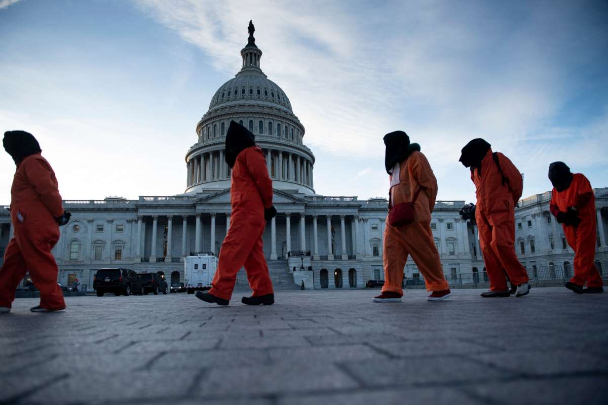 Demonstrators dressed in Guantanamo Bay prisoner uniforms march past Capitol Hill in Washington, D.C., on January 9, 2020, during a "No War with Iran" rally.
