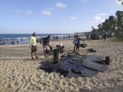 People clean up crude oil on a beach