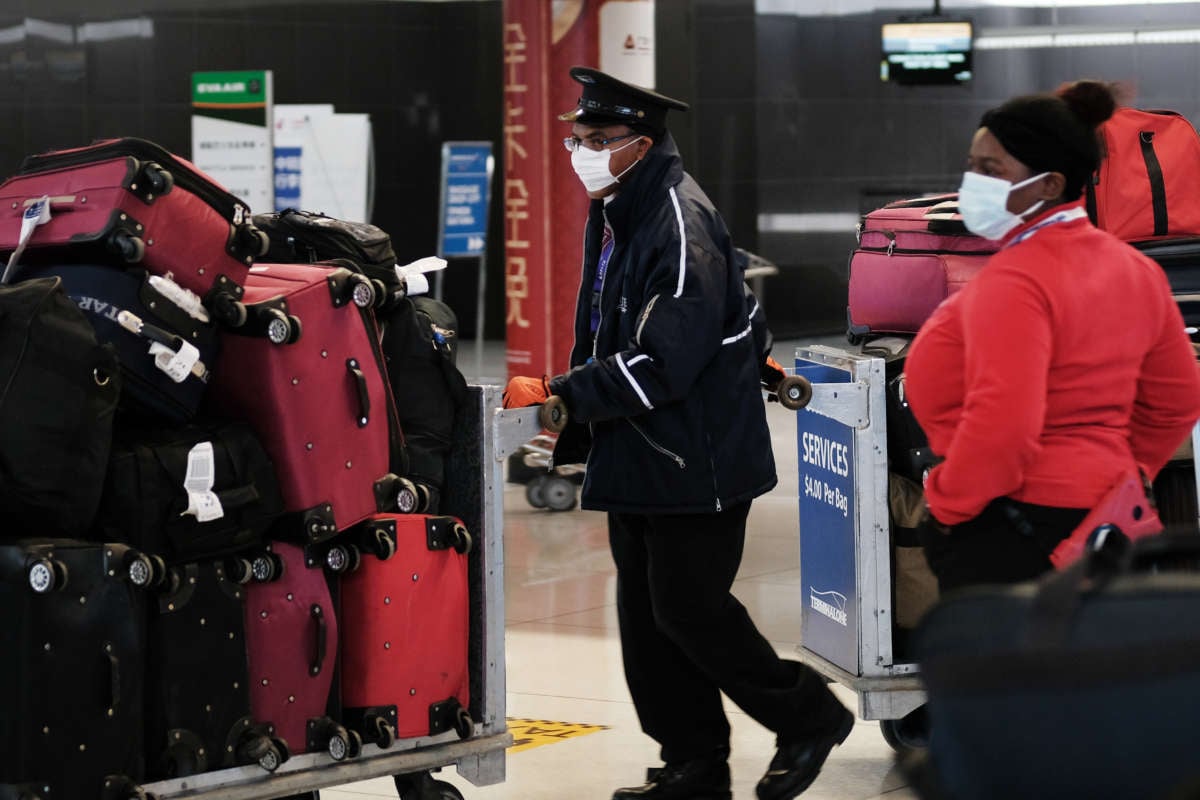Airport workers wear face masks as they handle luggage